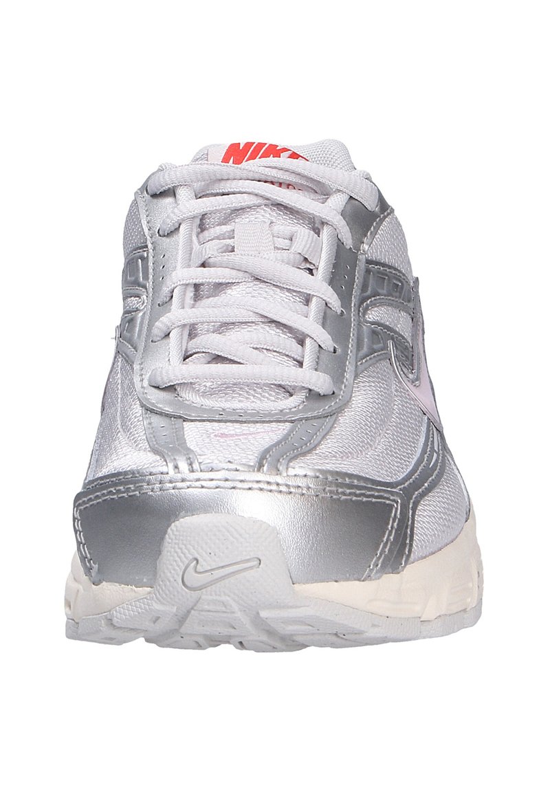 Zapatilla de running Nike con un upper sintético plateado y blanco, detalles en rosa claro y suela de goma. Los cordones son blancos y planos.