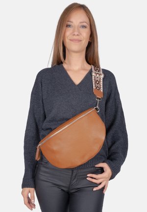 Braune Leder-Crossbody-Tasche mit runder Form, silbernem Reißverschluss und gemustertem Gurt. Die Tasche verfügt über eine strukturierte Oberfläche und eine Quaste als Detail.