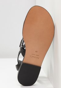 Sandale noire avec une semelle et un talon couleur tan, inclinée pour montrer le nom de la marque sur la semelle, la taille 38, et l'étiquette "VERO CUOIO".