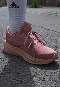 Roze sportschoen met een gestructureerde mesh bovenkant, gevoerde kraag en drie-strepenmerk. Beschikt over een dikke, gevoerde zool en veters.