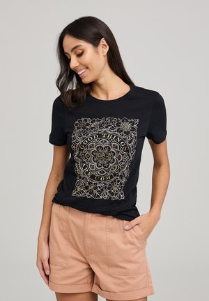 T-shirt in cotone nero con un intricato design floreale dorato e la scritta "BUONE COSE STANNO ARRIVANDO," scollo rotondo e maniche corte.