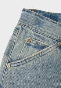 Világoskék farmernadrág, magas derékkal, kontrasztos varrással és egy apró, ferde elülső zsebbel, ami patenttal záródik.