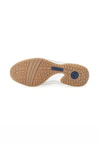 White sneaker with a flexible rubber sole. Textured brown outsole with dot patterns, featuring a blue logo label on the side.