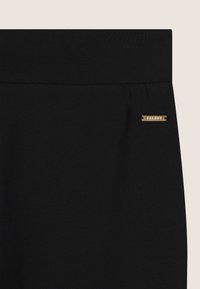 Pantaloni aderenti neri realizzati in tessuto morbido. Presentano una cintura liscia e un piccolo logo dorato "FREDDY" in evidenza. Design semplice e uniforme, senza fantasie.