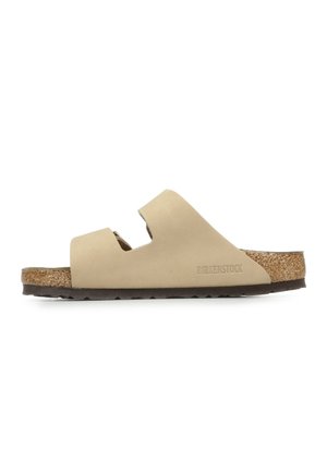 Sandalo beige con due cinghie regolabili, sottopiede in sughero e suola in gomma texturizzata. Logo "Birkenstock" impresso di lato.