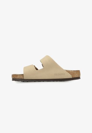 Sandalo beige con due cinghie regolabili, sottopiede in sughero e suola in gomma texturizzata. Logo "Birkenstock" impresso di lato.