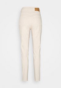 Beiga bomullsmixade byxor med smal passform, femficksdesign och en brun läderlapp på bakre midjebandet.