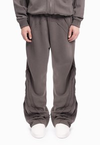 Grijze joggingbroek met een losse pasvorm, getextureerde naden en een gelaagde stofontwerp, met een lichte toelopende aansluitingen bij de boorden.