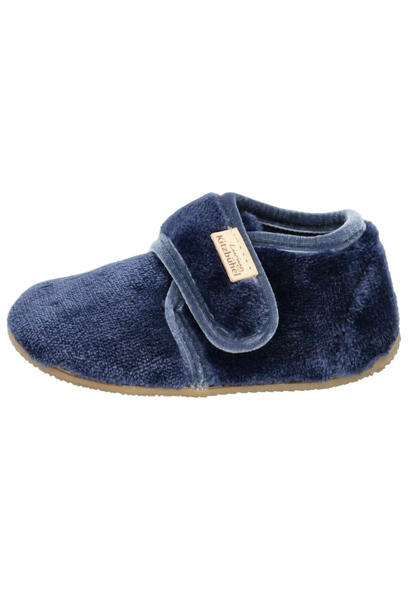 Chausson pour enfant en bleu marine doux avec une bride à scratch et une semelle marron clair, étiqueté "Kitzbühel".
