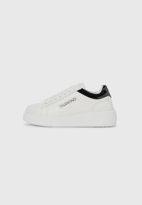 Hvite lerrets-sneakers med svarte lakk lærdetaljer; rund tå, tykk hvit såle, snøremekanisme og trykt "VALENTINO"-logo på siden.
