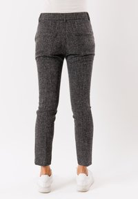 Pantaloni neri e grigi a motivo, dal taglio aderente, con vita elastica e due tasche posteriori. Abbinati a sneakers bianche.