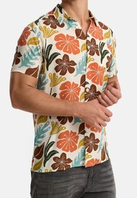 Camisa de manga corta de tejido ligero con un patrón floral multicolor que incluye detalles en naranja, marrón, verde y azul. Con botones en la parte delantera y un bolsillo.