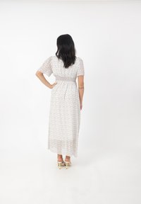 Abito maxi realizzato in tessuto leggero e trasparente, con un motivo floreale in colori pastello, maniche a puff corte e dettaglio in vita arricciato.