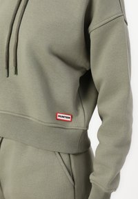 Olivgrünes Sweatshirt aus Baumwollmix mit regulierbarem Kapuzenzug, gerippten Bündchen und Saum, mit einem rot-weißen "HUNTER"-Logolabel.