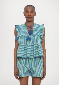 Top in cotone a righe blu e verde con maniche a volant, orlo peplum e scollatura annodata; abbinato a pantaloni corti a righe coordinati.