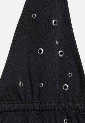 Čierna tkanina s viacerými kovovými očkami rôznych veľkostí usporiadanými náhodne, obsahujúca prišité švy a zatiahnutú elastickú časť.