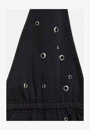 Čierna tkanina s viacerými kovovými očkami rôznych veľkostí usporiadanými náhodne, obsahujúca prišité švy a zatiahnutú elastickú časť.