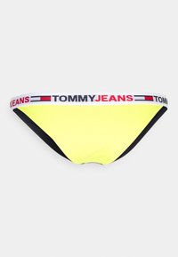 Parte de baixo de bikini amarelo neon com laterais pretas e uma faixa branca com o logótipo "TOMMY JEANS" em vermelho e preto. Textura suave.