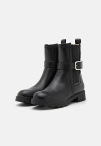 Bottines en cuir noir avec une finition lisse, sangle décorative extérieure, accent de boucle en argent et semelle en caoutchouc texturée pour une bonne adhérence.
