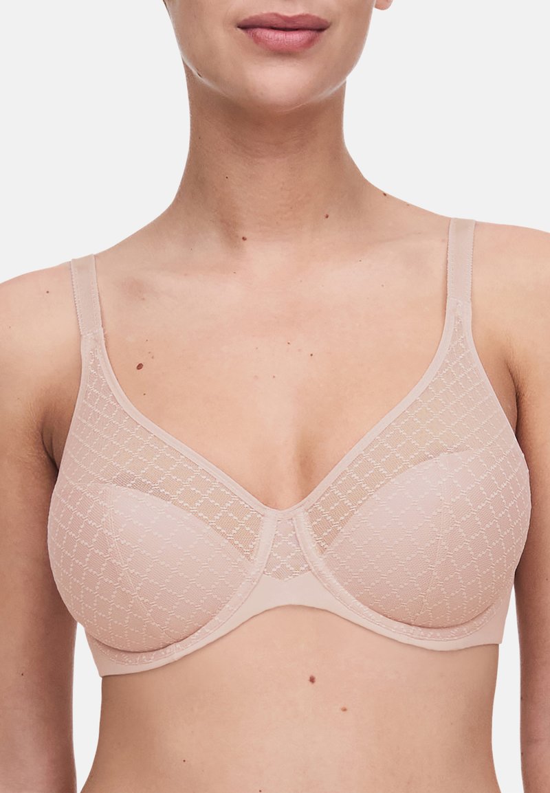 Beige bh med gennemsigtigt mønstret stof, underwire støtte, justerbare stropper og glat tekstur. Har et geometrisk diamantmønster.