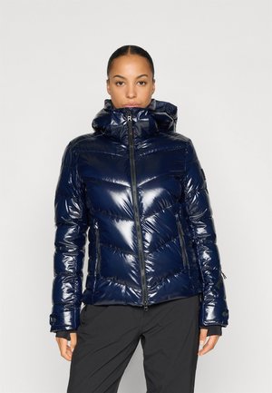 Giacca a vento trapuntata blu navy, lucida, con cappuccio, chiusura con zip e motivo a chevron. Presenta polsini elasticizzati e tasche laterali con zip.