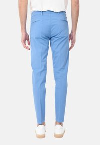 Pantaloni azzurri chiari in cotone, con una vestibilità slim, tasche posteriori e una superficie liscia, abbinati a sneakers bianche.