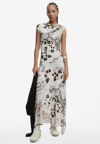 Rochie maxi dintr-un material ușor, cu un amestec de imprimeuri animale și modele abstracte în nuanțe de bej, negru și maro. Decolteu drapat, design fără mâneci.