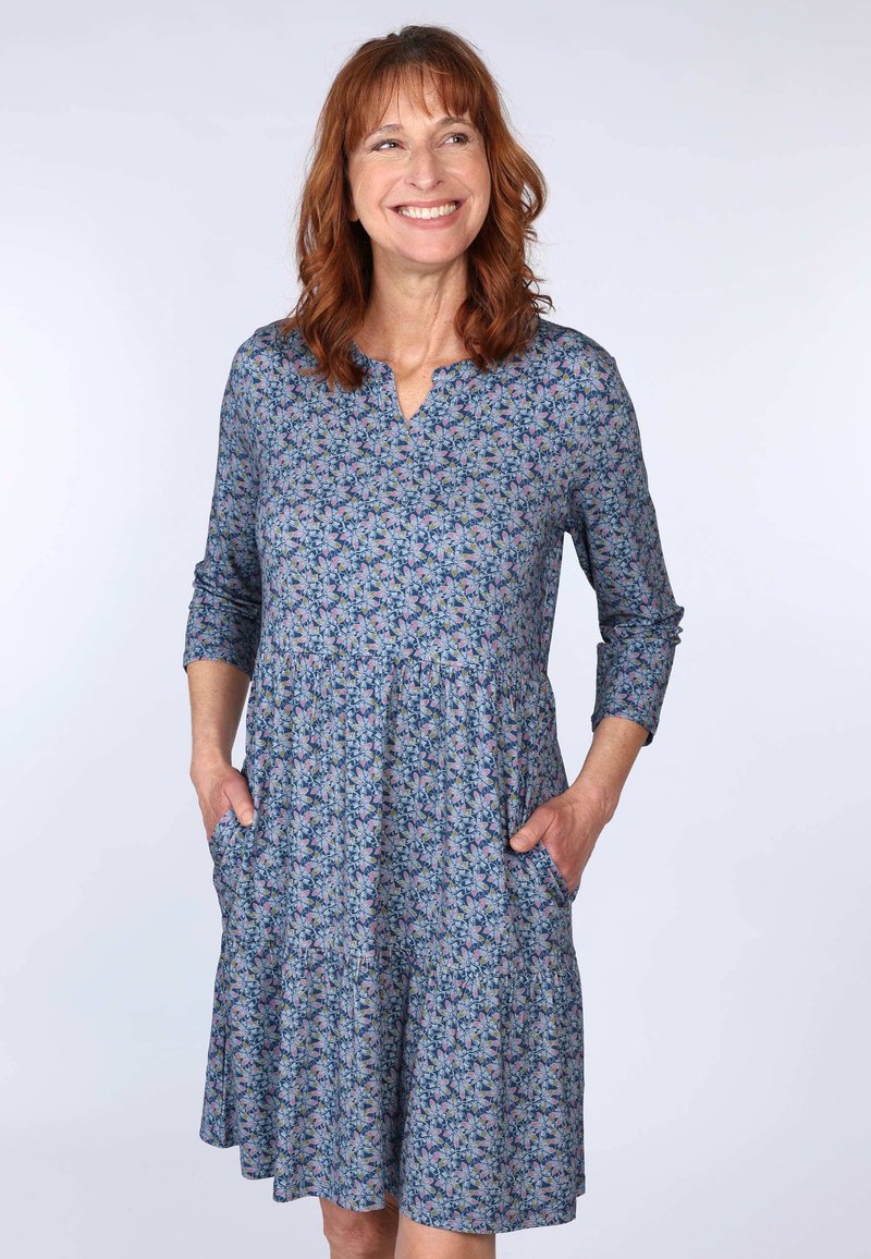 Blumenkleid aus Baumwolle mit einem blauen Hintergrund und pinken sowie grünen Mustern, V-Ausschnitt, Dreiviertelärmeln und seitlichen Taschen.