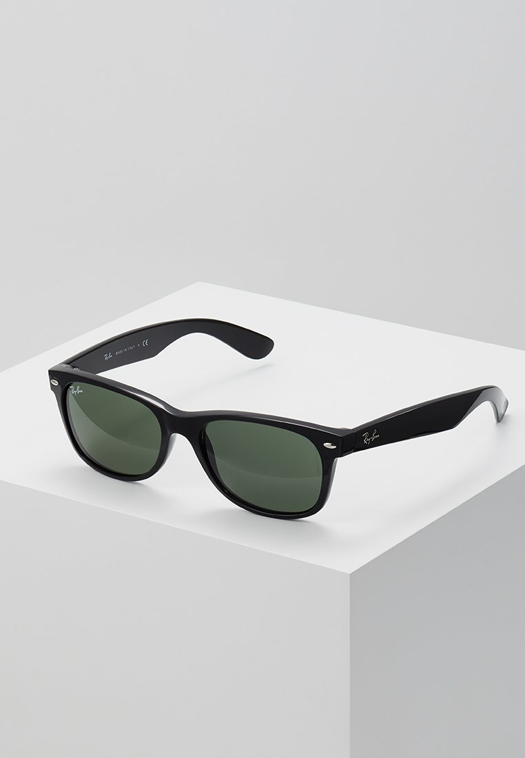 Occhiali da sole in plastica nera con lenti verdi, caratterizzati da una forma rettangolare e una parte superiore piatta, con accenti metallici sulla montatura.