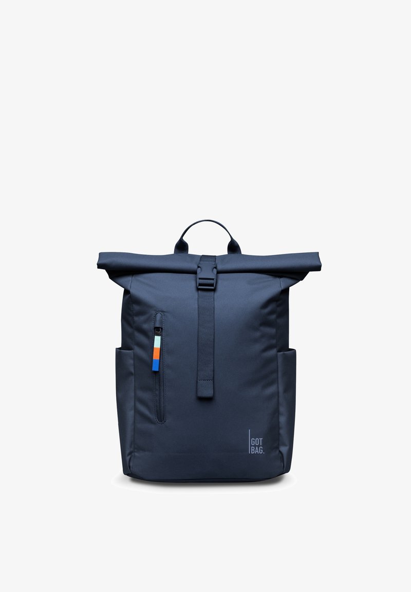 Granatowy plecak z rolowaną górą, zapinany na zamek z przodu, z bocznymi kieszeniami, górnym uchwytem oraz logo "GOT BAG" w dolnym prawym rogu.