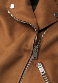 Giacca in suede marrone con cerniera argento e dettagli a scatto, dal texture morbido e un design con collo drappeggiato.