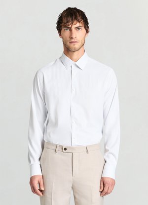 Chemise blanche à manches longues avec fines rayures verticales, col classique et devant à boutons. Associée à un pantalon beige orné d'un bouton en accent.