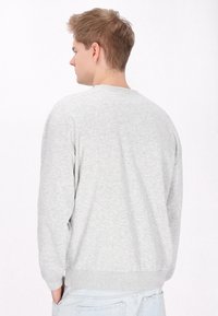 Lys grå sweatshirt med rund halsudskæring, s�ænkede skuldersømme og ribbede ærmer og kant. Blødt, tekstureret stof med en afslappet pasform.