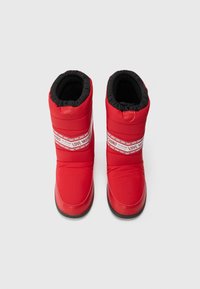Piros párnázott csizmák fekete béléssel, a középső részen egy kiemelkedő fehér csíkkal, amelyen a "LOVE MOSCHINO" felirat szerepel. Simább felület, kerek orr.