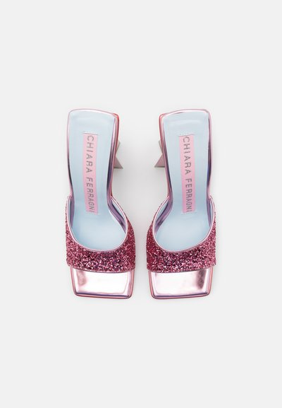 Rožnate bleščeče sandale s peto in kvadratnim prstom ter kovinskimi detajli. Peta je v obliki bloka, notranjost pa vsebuje svetlo modro vložek.