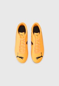 Oransje fotballsko med en glatt overflate, med svarte Puma-logoer, flate lisser og en polstret, svart indre fôr.