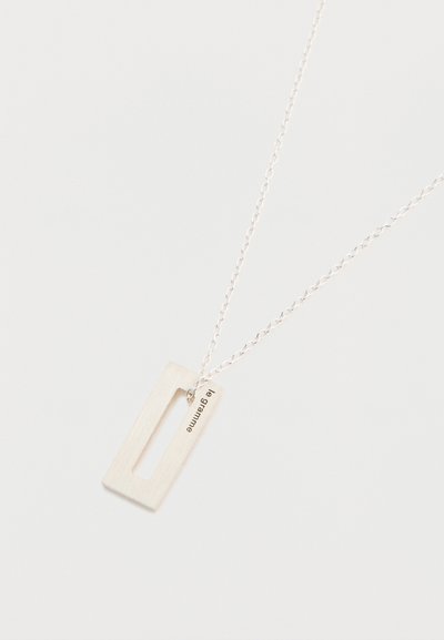 Lănțișorul cu pandantiv din argint are un design rectangular cu un centru decupat, atașat de o lanț subțire. Este gravat cu "le gramme."