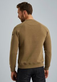 Olivgrüner Sweatshirt mit gerippten Bündchen und Saum, mit RaglanÄrmeln und einem kleinen Patch auf der linken Schulter. Glatte Textur.