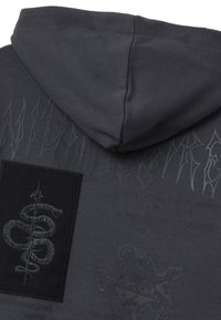 Felpa con cappuccio grigio scuro caratterizzata da un logo in rilievo testurizzato, con cappuccio e una patch nera che presenta un design di serpente. Dettagli grafici chiari distribuiti su tutto il capo.