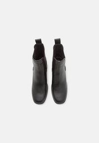 Botas de cuero negro hasta el tobillo con punteras redondeadas, paneles laterales elásticos, tiradores y textura lisa. El diseño es elegante y minimalista.
