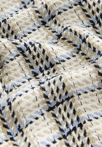 Tessuto intrecciato con motivo a spina di pesce in crema, azzurro chiaro e nero, con un aspetto strutturato e una caduta morbida.