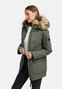 Olivgrön parkasjacka med huva i päls, dragkedja framtill, sidofickor, ribbade ärmslut och avslappnad passform. Texturerat tyg.