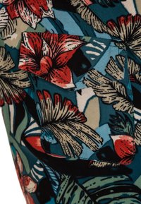 Floral-patterned fabric featuring large red flowers and green leaves on a turquoise background, with a patch pocket detail visible.