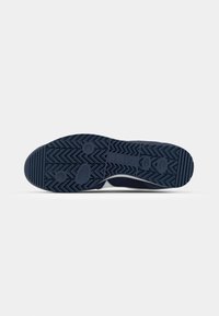 Marine blå sneakersåle med teksturert gummi, med en sikksakk mønster. Inkluderer en hvit accent langs siden og merkevaredetalj.
