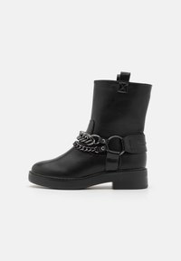 Bocanc negru din piele, până la gleznă, cu toc robust, dotat cu o curea decorativă din lanț argintiu și detaliu cu cataramă pe lateral. Textură netedă, design minim.