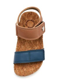 Sandal de cuero marrón y azul con suela de corcho, que presenta dos correas ajustables y un acento metálico. Textura suave con un diseño plano.