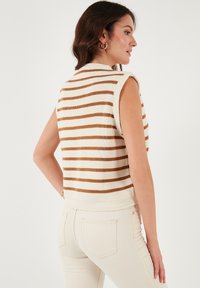 Gebreide mouwloze top met horizontale beige en bruine strepen, kenmerkend door een hoge halslijn en een cropped pasvorm, met een textuur van ribbeldetails.