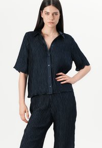 Camicia blu navy con tessuto texture e stropicciato, maniche corte, colletto classico e taglio rilassato.