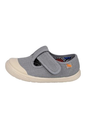 Zapato de lona gris para niños con puntera de goma, cierre de velcro, forro interior con estampado y suela beige texturizada.