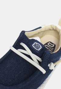 Scarpe in tela blu con lacci bianchi, punta rotonda e fodera beige chiaro. Presentano un'etichetta con il marchio sulla linguetta e una suola testurizzata.